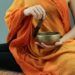 person in orange scarf holding silver round bowl